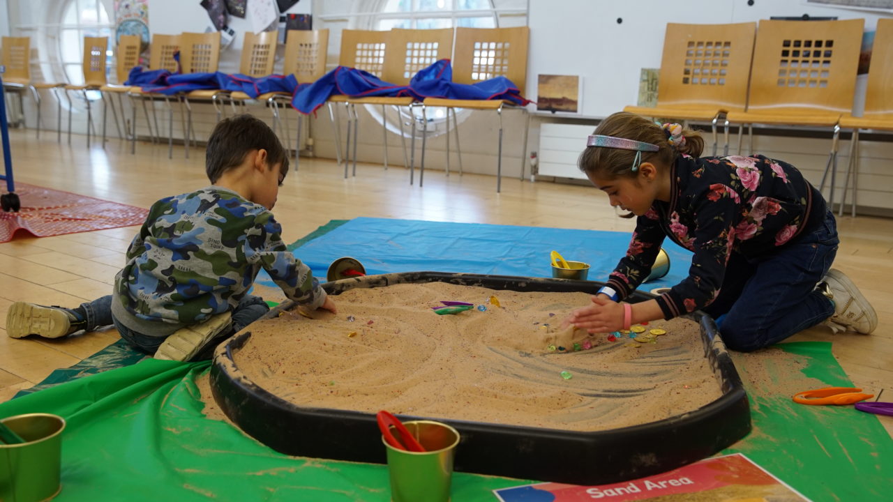 Two young children play in a sandbox.