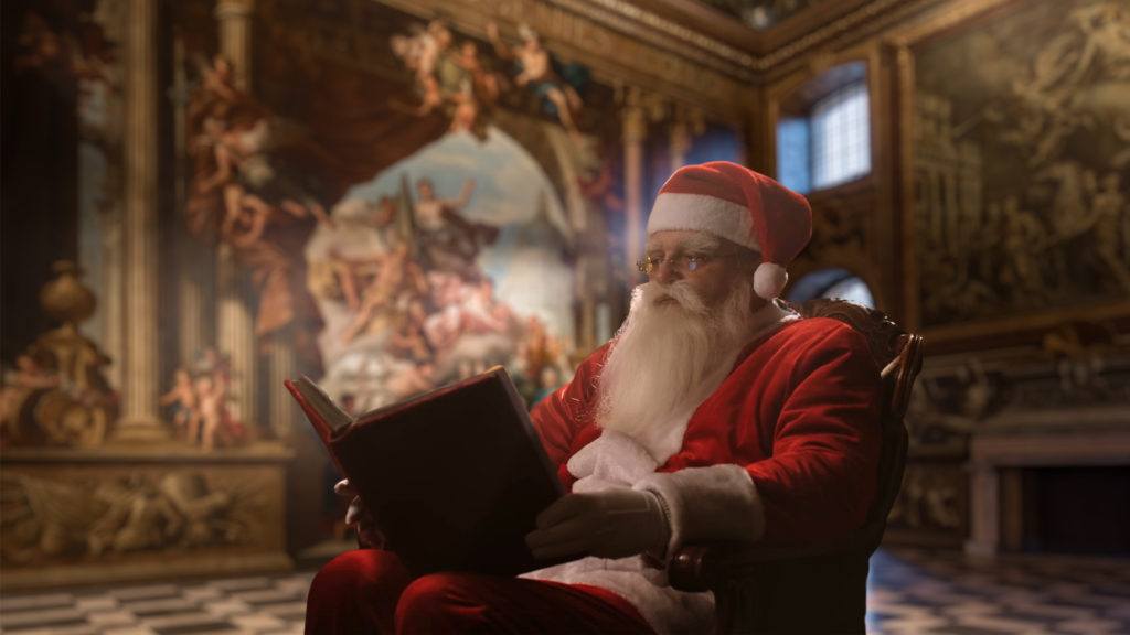 A man dressed up as Father Christmas reads a book inside the Painted Hall.