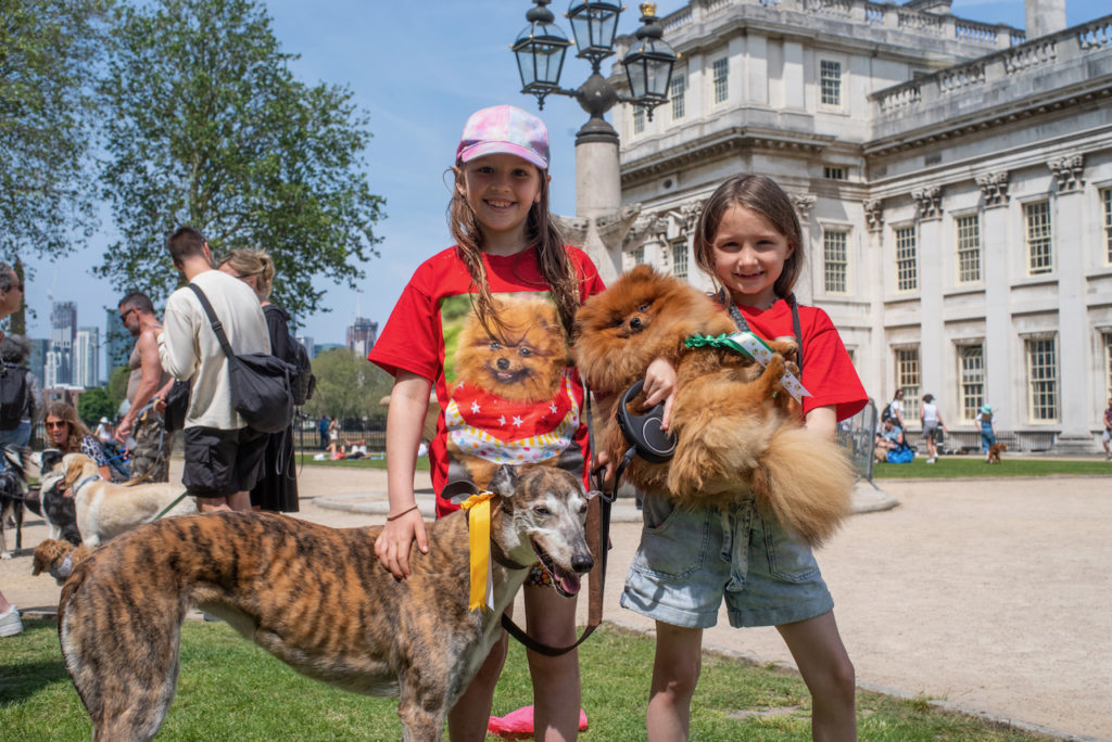 two childs holding dogs in front of Old Royal Naval College building