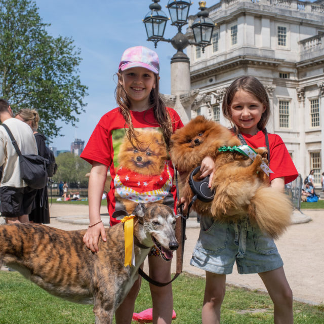 two childs holding dogs in front of Old Royal Naval College building