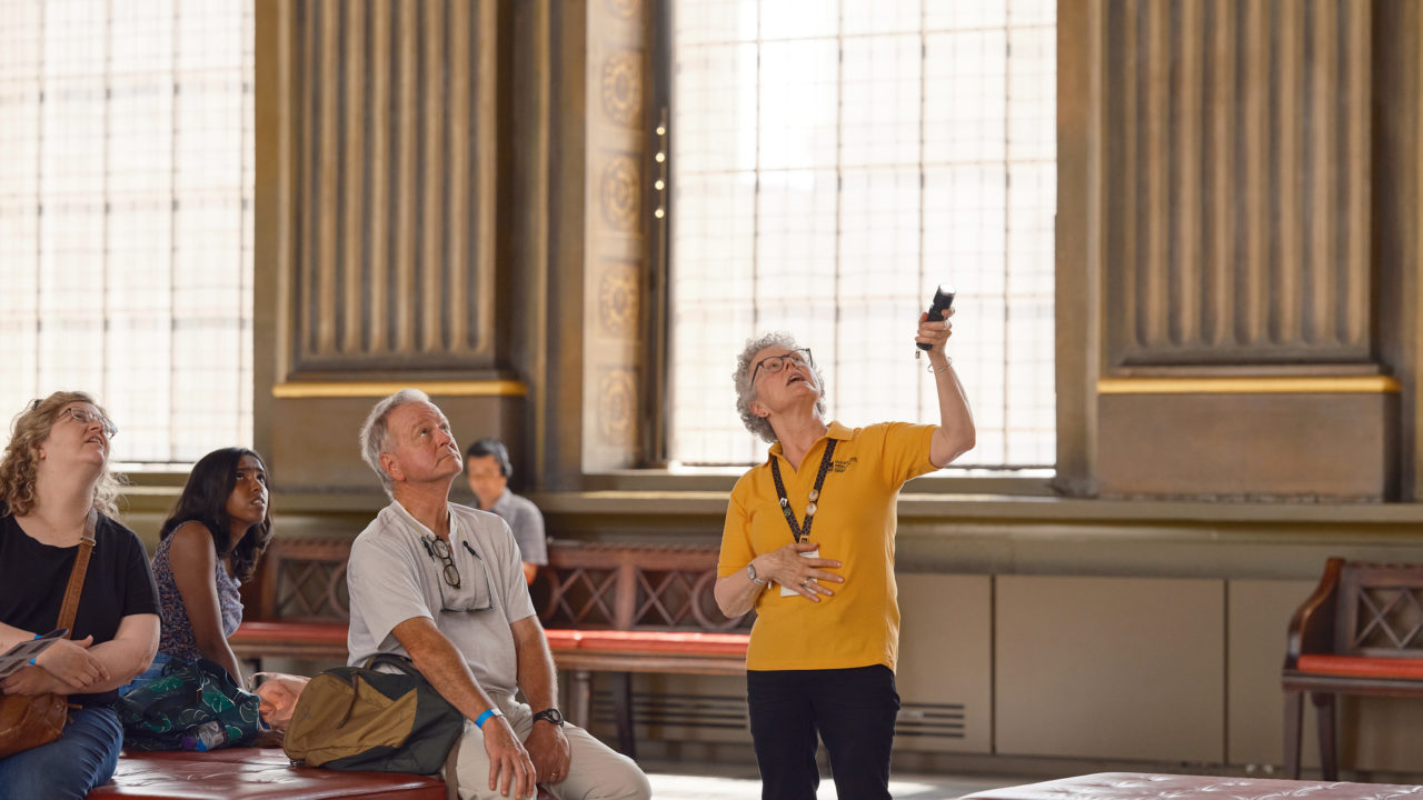 Guide pointing in tour of Painted Hall